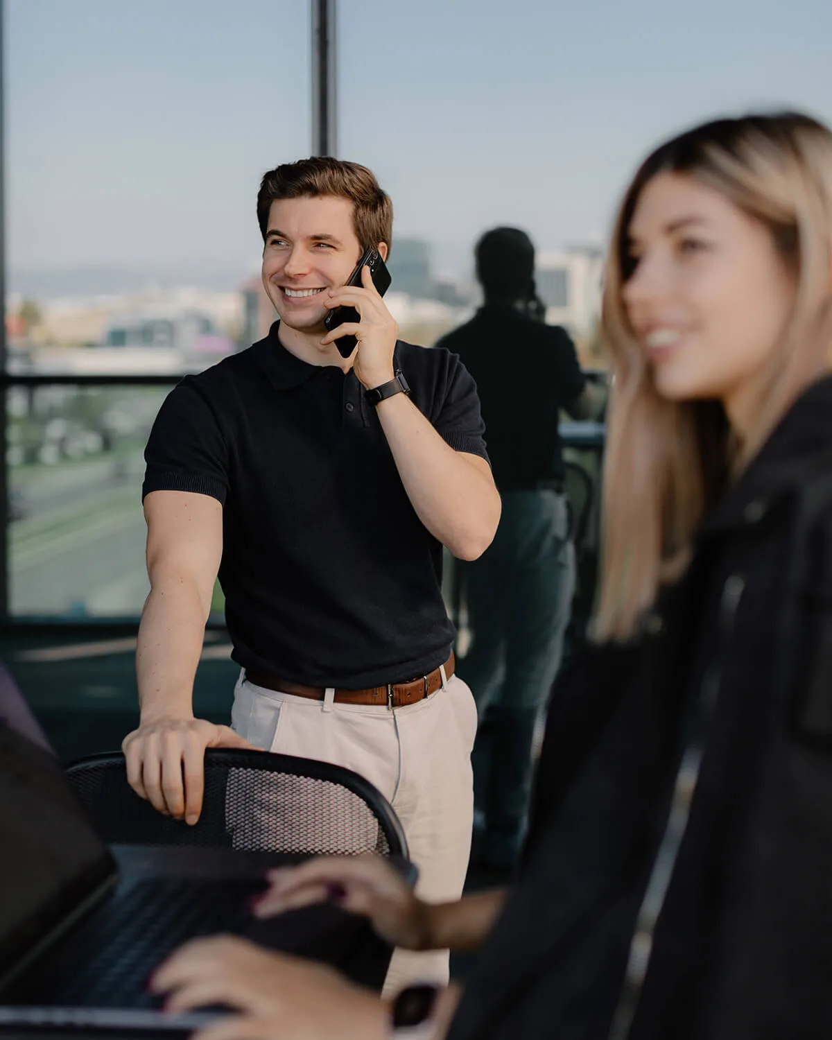 A smiling man on a phone call and a smiling woman on her laptop