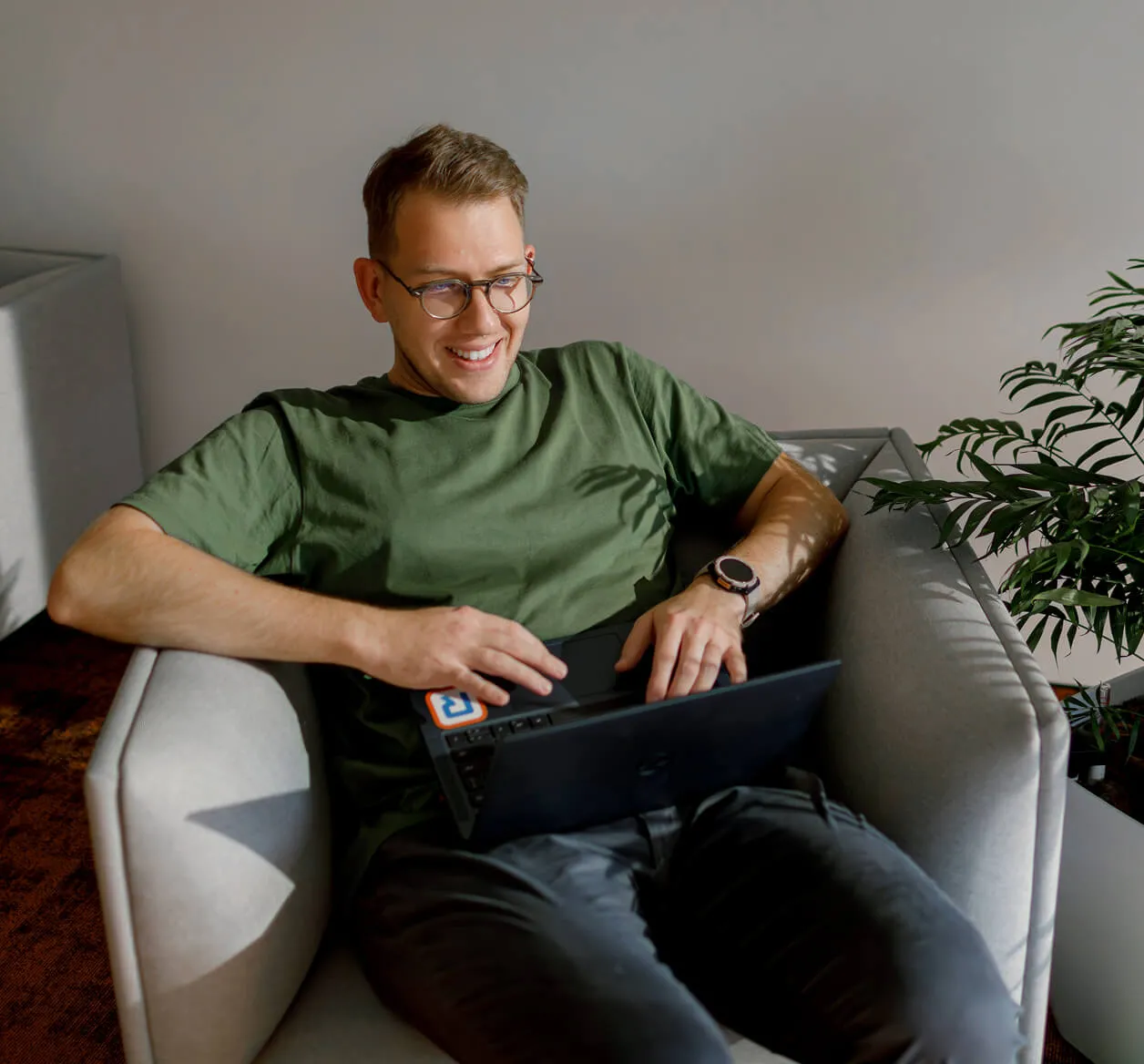 A smiling RingCentral employee sitting on a couch with his laptop