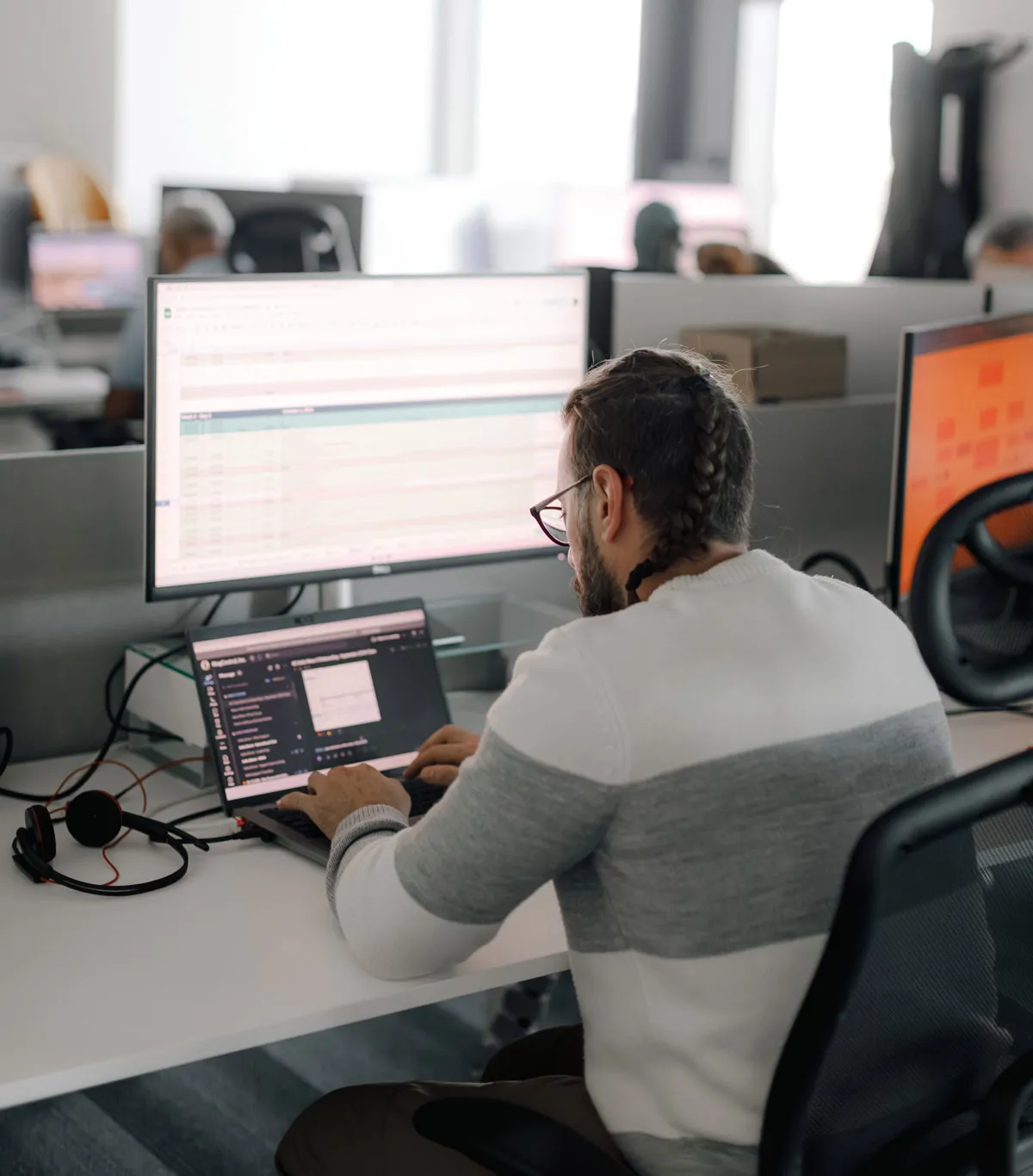 A developer coding on his laptop with a wide screen above