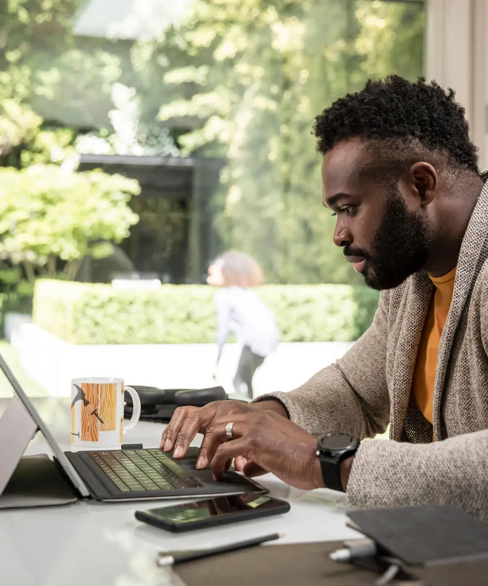 A male using his laptop and mobile to work from home