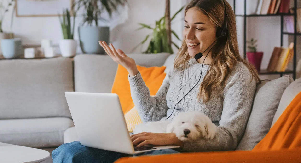 A woman working from home with a dog on her lap