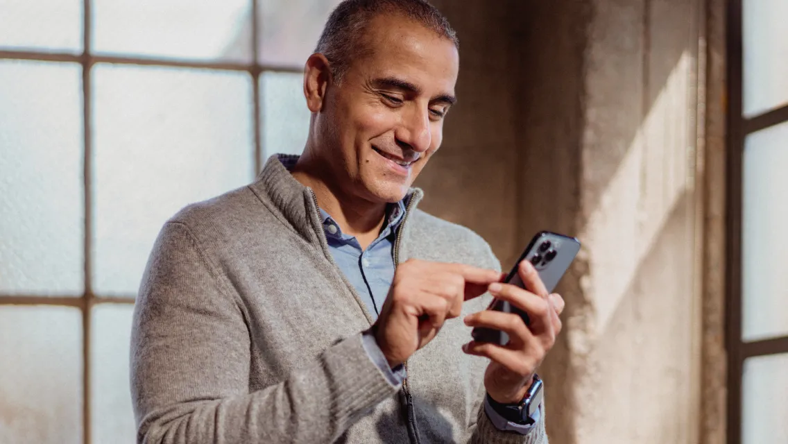 A man smiling while holding his mobile phone