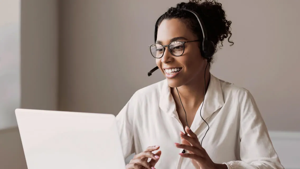 A female agent on her headset while looking at a laptop