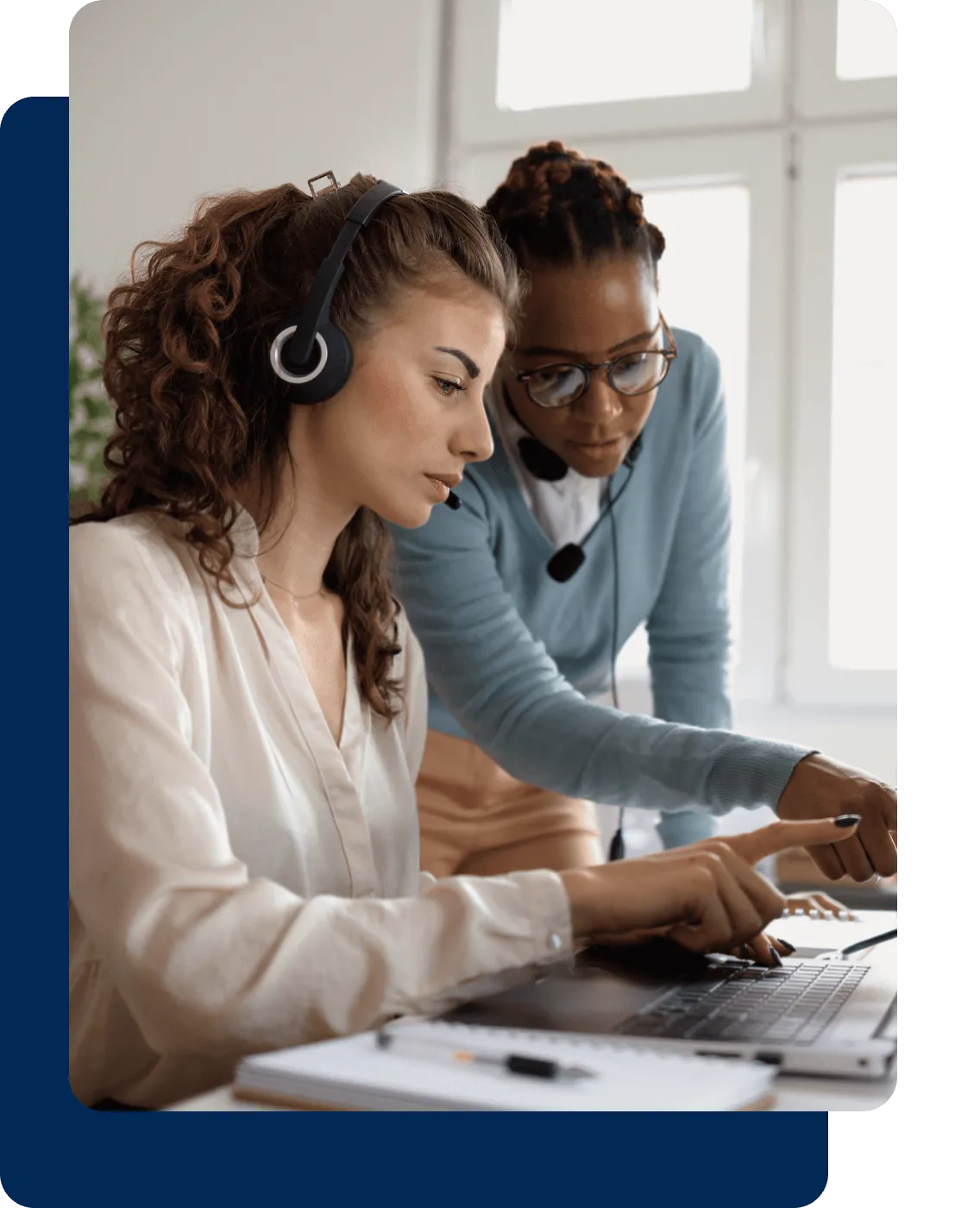 Two female contact center workers looking at a laptop