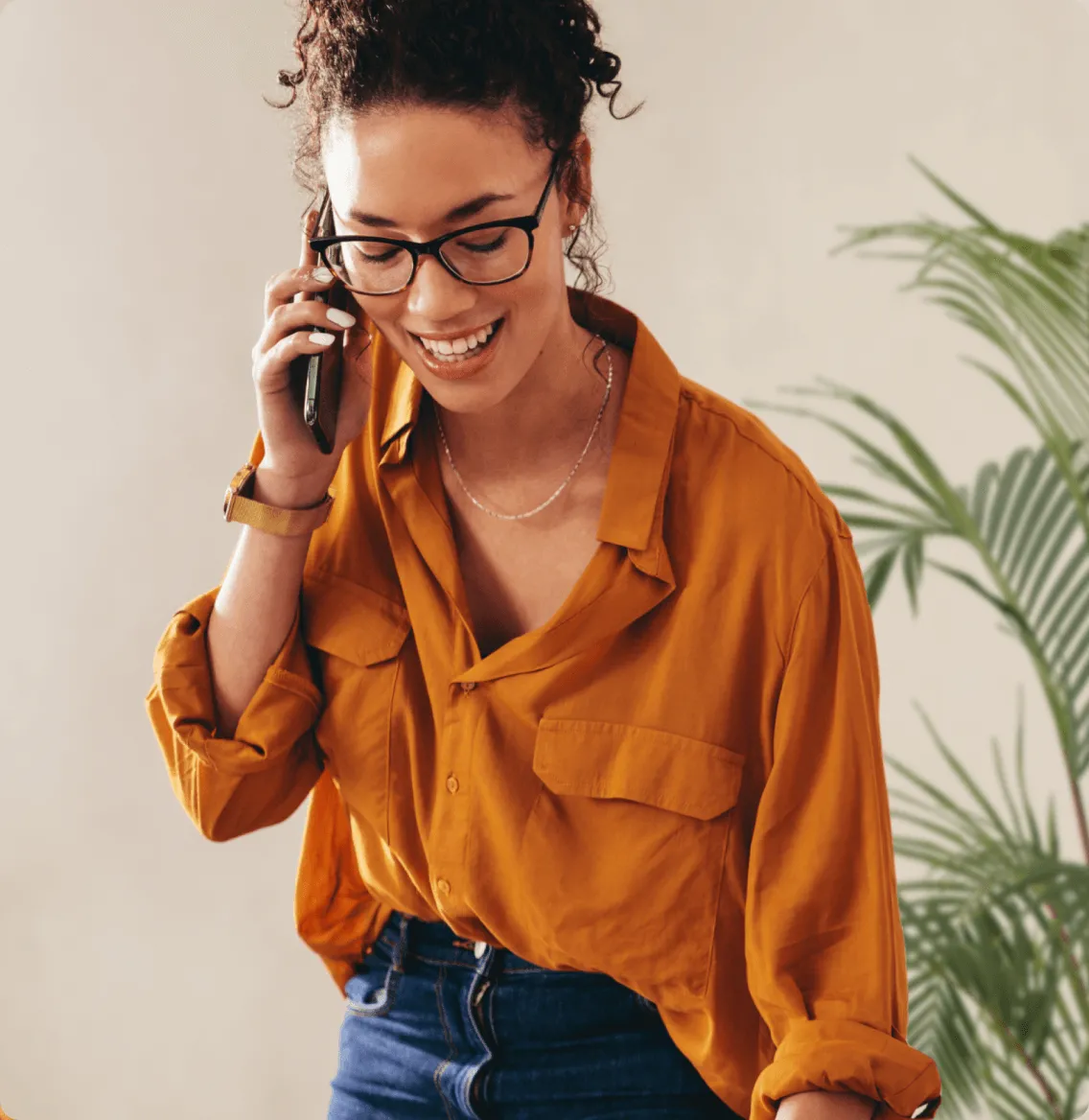 A woman on a call on her mobile phone with plants in the background