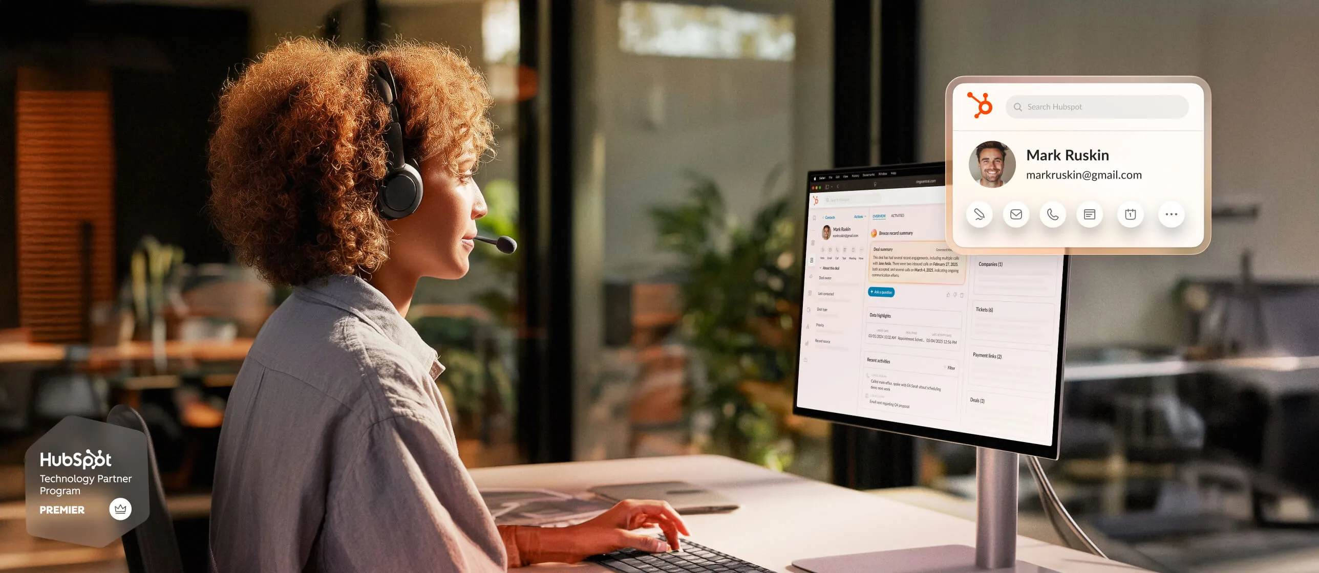A professional using a computer in an office, engaging with a customer interface on the screen using a headset.