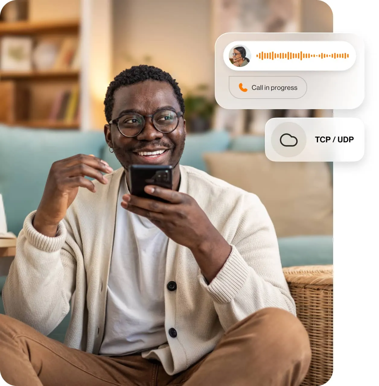 A smiling man sitting on the floor is in a recorded phone call on his mobile phone