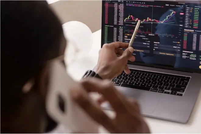 A man analyzing a graph on his laptop while on a phone call