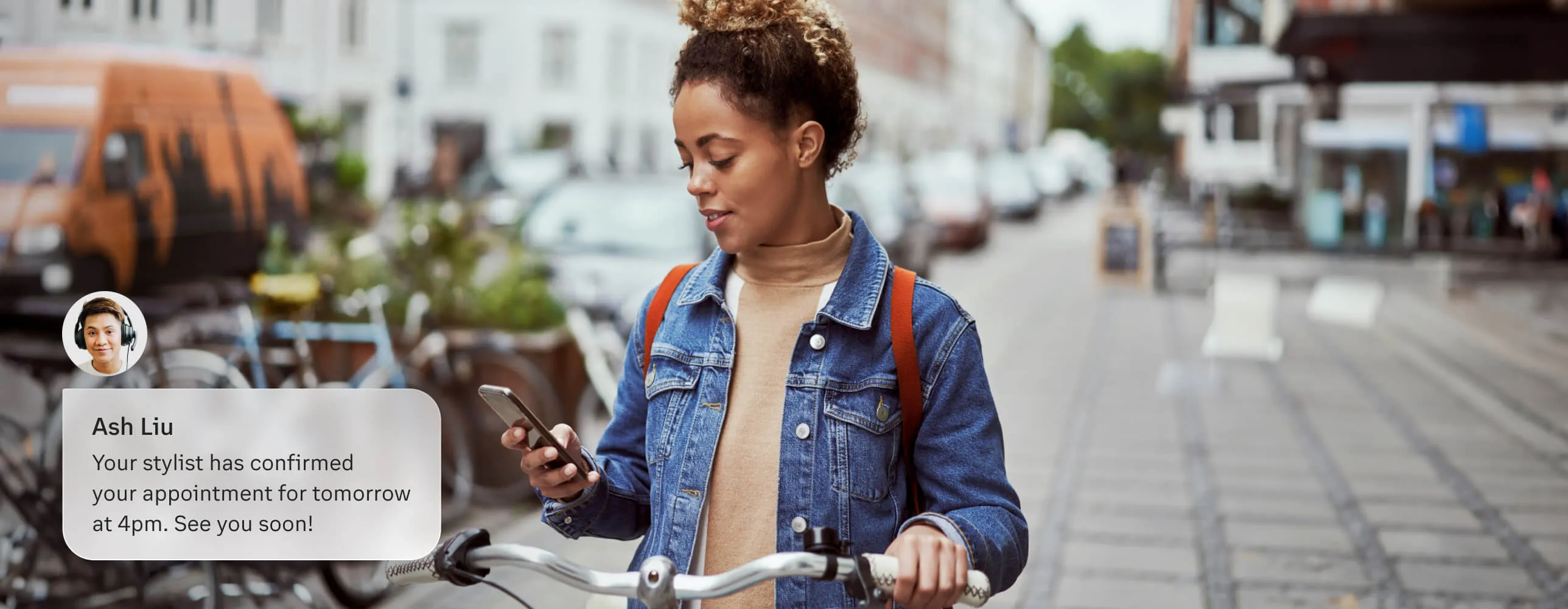 A woman receives a Business SMS notification on her phone regarding her appointment with a stylist