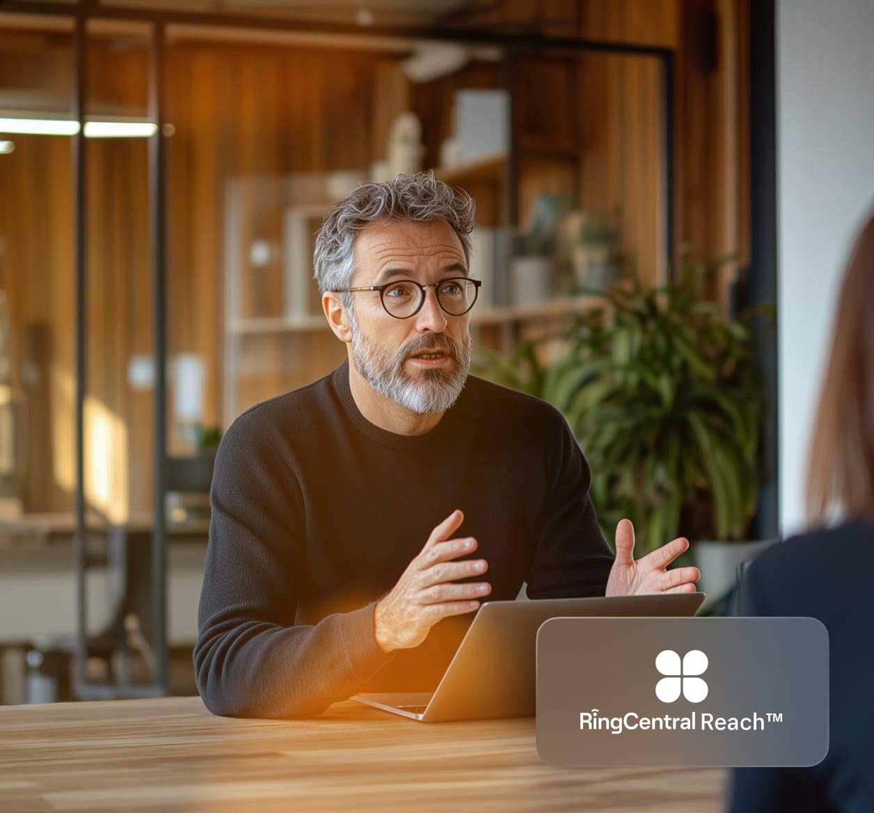 A man in glasses explaining to a woman across the table with inlay of RingCentral Reach logo