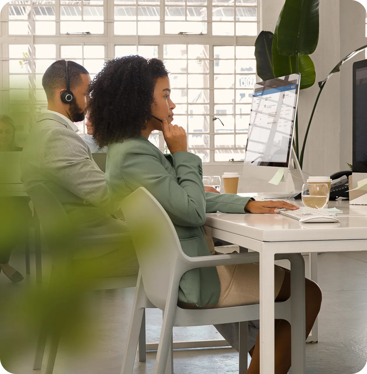 A couple of contact center agents making outgoing call while on a white desk