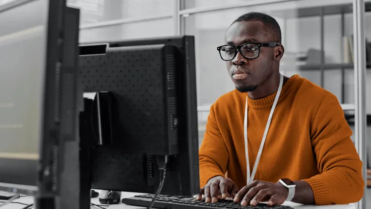 Un homme regarde son écran tout en tapant sur son clavier