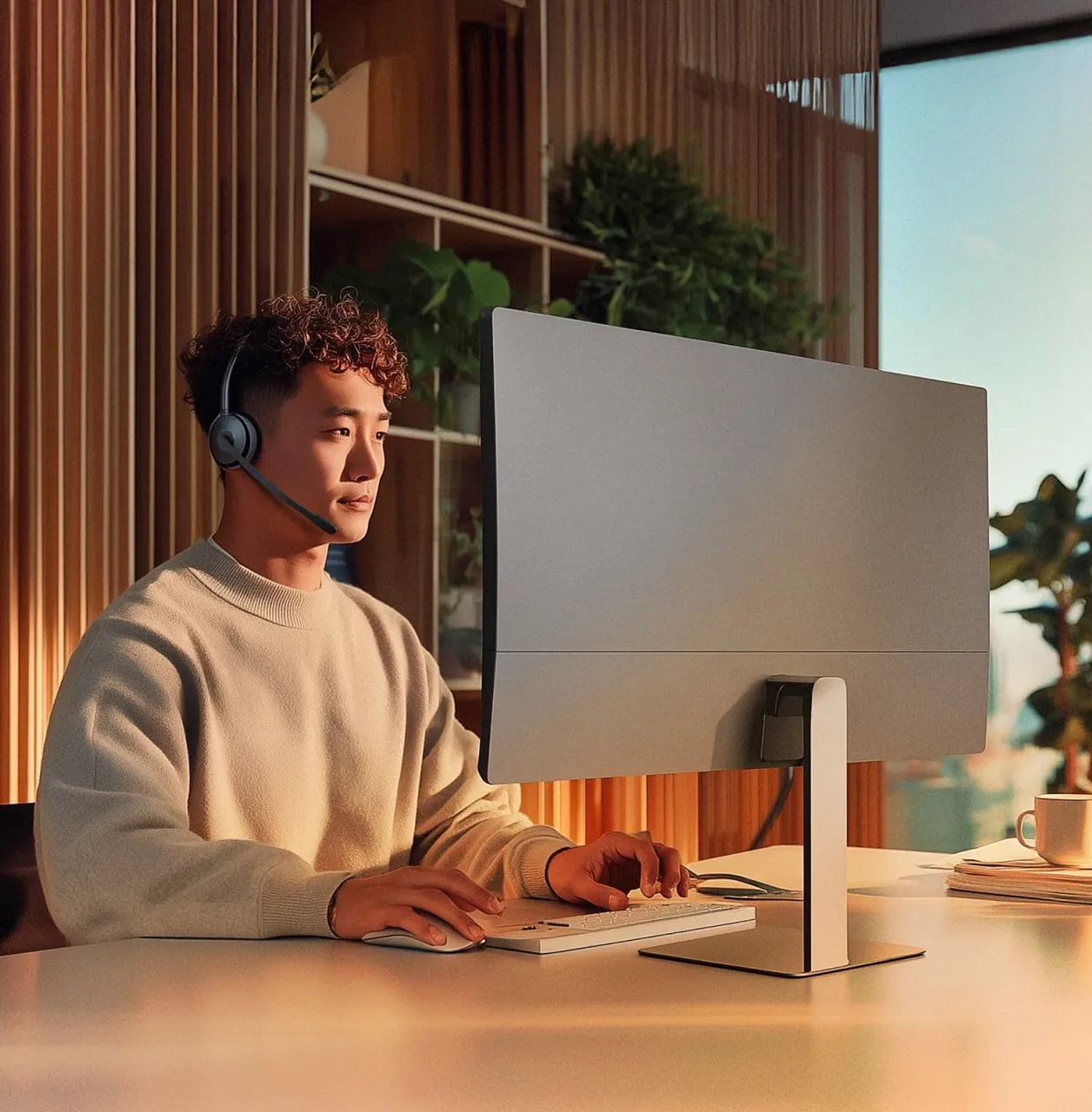 Person wearing headphones working at a computer desk.