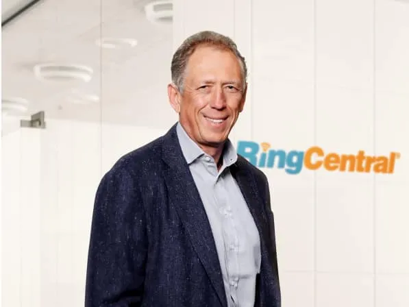 RingCentral CEO Vlad Shmunis stands in front of a wall with the RingCentral logo.